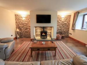a living room with a fireplace with a couch and a table at Orcaber Farm Barn in Austwick