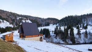 a small building on a snowy hill with trees at Owl House Jelovica in Berane