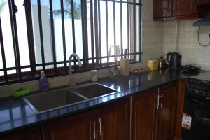 eine Küchentheke mit einem Waschbecken und einem Fenster in der Unterkunft Havana Comfort in Daressalam