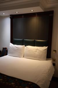 Cette chambre comprend un grand lit avec des oreillers blancs. dans l'établissement Dreamtel London Kensington, à Londres