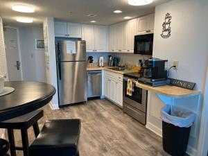 a kitchen with a stainless steel refrigerator and a table at 2501 S Ocean Blvd, 1101 - Ocean Front Sleeps 8 in Myrtle Beach