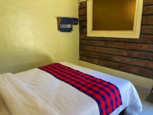 - une chambre avec un lit et une couverture dans l'établissement Lulunga Eco Lounge and Farm, à Narok