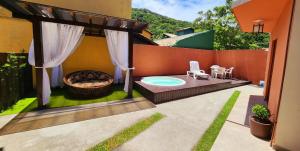 un patio trasero con bañera de hidromasaje y zona para hacer hogueras en Partiu Praia SC en Guarda do Embaú