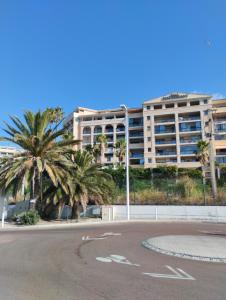 Un estacionamiento vacío con palmeras y un gran edificio. en Ciel Bleu de Cannes - Appartement Vue Azur avec Piscines et Jardin, en Cannes