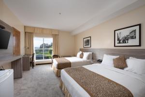 a hotel room with two beds and a flat screen tv at Days Inn by Wyndham Surrey in Surrey