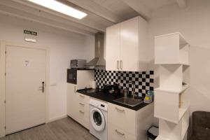 uma cozinha com armários brancos e uma máquina de lavar roupa em Loft atenas em León