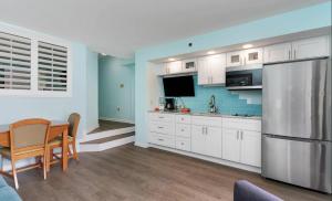 cocina con armarios blancos, mesa y nevera en 4800 S Ocean Blvd, 0915 - Ocean Front Sleeps 6 en Myrtle Beach