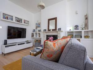 a living room with a gray couch and a television at Shirlock Home - Italianflat in London