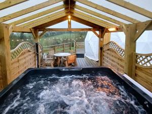 bañera de hidromasaje en la terraza de un cenador en Little River Glamping en Ballymoney