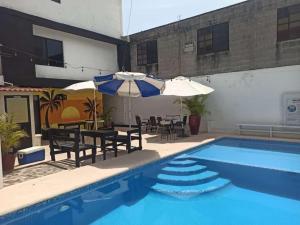 坦皮科的住宿－Hotel Vithez，一座带椅子和遮阳伞的游泳池位于一座建筑旁边
