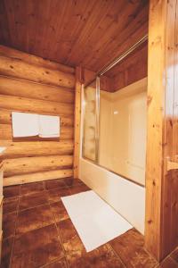 a bathroom with a shower and a tub in a wooden room at Rocky Mountain Escape Log Cabin Rentals - Rock Lake in Rock Lake Provincial Park