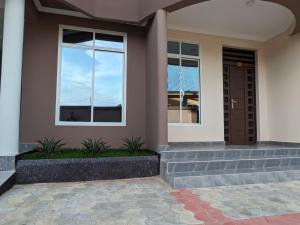 uma casa com duas janelas e uma porta em Suji House em Dodoma