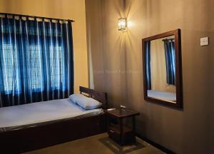 een kleine kamer met een bed en een spiegel bij Liyara Nature Farm Resort in Gampaha