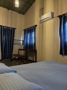 een slaapkamer met blauwe gordijnen en een bed en een tafel bij Liyara Nature Farm Resort in Gampaha