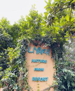 a sign for a nicaarine farm resort covered in plants at Liyara Nature Farm Resort in Gampaha