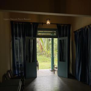 an open door to a room with blue curtains at Liyara Nature Farm Resort in Gampaha