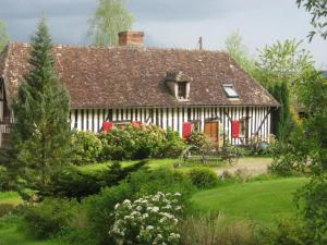 una casa con puertas rojas y un patio verde en La Boursaie en Livarot