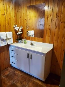 La salle de bains est pourvue d'un lavabo blanc et d'un miroir. dans l'établissement Rocky Mountain Escape Log Cabin Rentals - Rock Lake, à Rock Lake Lodge Provincial Park
