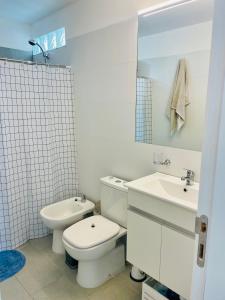 a white bathroom with a toilet and a sink at Nuevo y confortable apto con parrilla in Montevideo