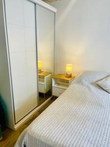 a bedroom with a bed and two night stands with lamps at Nuevo y confortable apto con parrilla in Montevideo