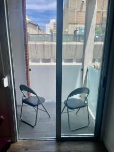 2 sillas sentadas en un balcón con vistas a la ventana en Nuevo y confortable apto con parrilla, en Montevideo