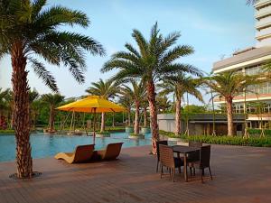 a table and chairs with a yellow umbrella next to a pool at Comfort One Bed Room Apartment Gold Coast PIK in Jakarta