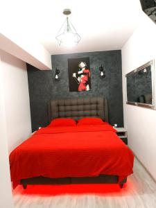 Un dormitorio con una cama roja con una foto en la pared en Dream Arena Apartment en Bacău
