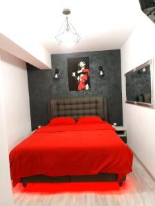 a bedroom with a red bed with a picture on the wall at Dream Arena Apartment in Bacău