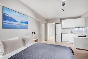 a white bedroom with a large bed and a kitchen at Bispegata 5 - Studio Apartment hotel in Tromsø