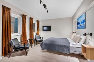 1 Schlafzimmer mit einem Bett und 2 Stühlen sowie einem TV in der Unterkunft Bispegata 5 - Studio Apartment hotel in Tromsø