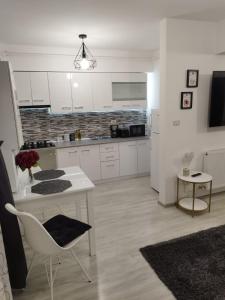 cocina con armarios blancos, mesa y silla en Dream Arena Apartment en Bacău