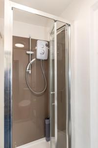 a shower with a glass door in a bathroom at Chic Studio Apartment, Bus 18 to Euston in 30 min. in London
