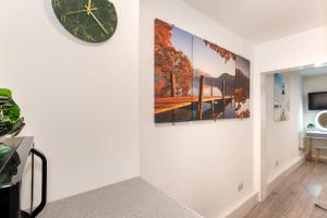 a hallway with three paintings on the wall and a clock at Chic Studio Apartment, Bus 18 to Euston in 30 min. in London