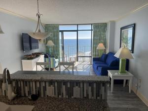 Sala de estar con sofá azul y vistas al océano en 74th Ave N, 1443-44 - Ocean View Sleeps 8 en Myrtle Beach