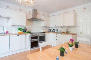 a kitchen with white cabinets and a wooden table at Sea Front Spacious Apartment on Anglesey in Brynsiencyn