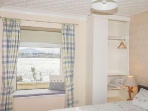 a bedroom with a window with a view of the water at Sea Front Spacious Apartment on Anglesey in Brynsiencyn