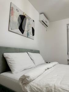 ein Bett mit weißer Bettwäsche und ein Gemälde an der Wand in der Unterkunft Apartman Maja in Srbobran