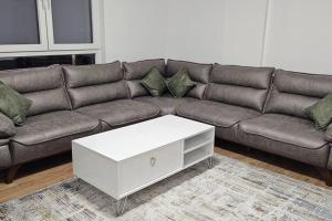 ein braunes Sofa mit einem weißen Couchtisch im Wohnzimmer in der Unterkunft The Cozy Flat in Gjakove