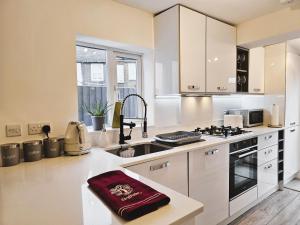uma cozinha com armários brancos e um lavatório em MAGICAL HARRY POTTER HOME IN WATFORD with FREE off-street PARKING em Watford