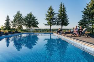 a group of people sitting around a swimming pool at Prohipo Stables - Romantic Rooms in Wysin