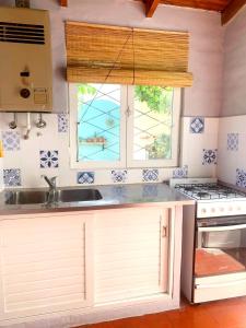 kuchnia ze zlewem, kuchenką i oknem w obiekcie La magnolia casa de alquiler temporario w mieście Puerto Madryn +17 zdjęć