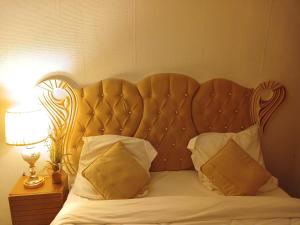 a bed with a wooden headboard and two pillows at PARADIS CHAMBRES D'HÔTES PROCHE PARIS - AÉROPORT CHARLES DE GAULLE AIRPORT - PARC DES EXPOSITION VILLEPINTE - DYSNAYLAND PARIS. in Tremblay En France