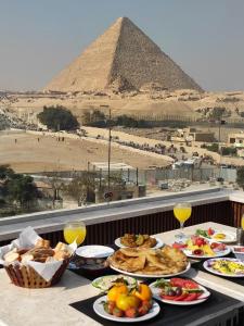 una tavola ricoperta di piatti di alimenti con una piramide sullo sfondo di Giza Pyramids View Inn a Il Cairo