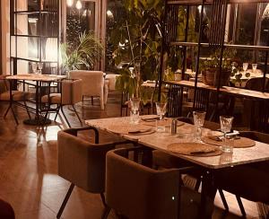 um restaurante com mesas, cadeiras e plantas em Hôtel Spa Restaurant La Madrague em Lucciana