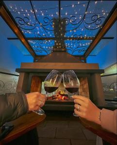 two people holding wine glasses in front of a fireplace at Blumen Hotel Boutique in Canela