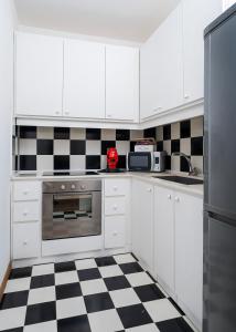 a kitchen with white cabinets and a checkered floor at Casa Zara Sorrento City Center in Sorrento