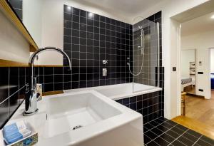 La salle de bains est pourvue de carrelage noir, d'un lavabo et d'une douche. dans l'établissement Casa Zara Sorrento City Center, à Sorrente