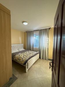 1 dormitorio con cama y ventana en Candy's Staycation en Thika