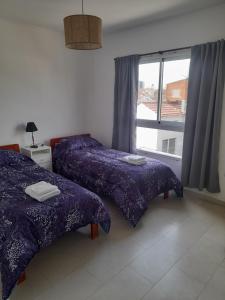 two beds in a room with a window at Super Departamento amplio y luminoso con cochera in Lanús