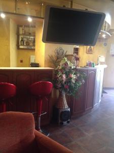 a bar with a vase of flowers and a tv at Family Hotel Silvestar in Veliko Tŭrnovo